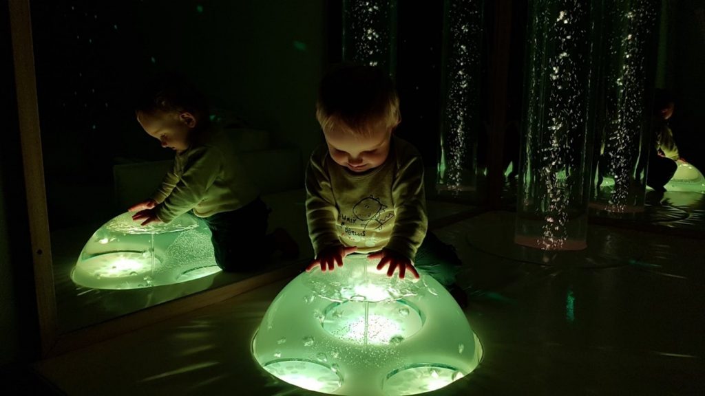 child looking into illuminated bubble, smiling
